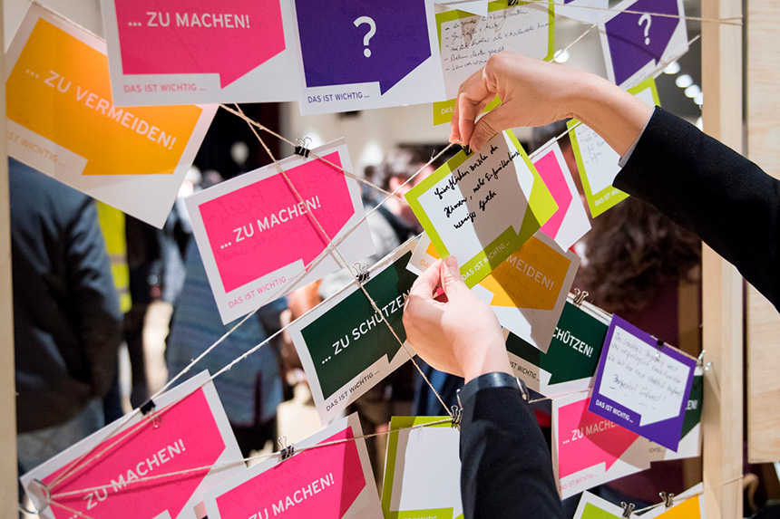Eine Person hängt eine Notiz an eine Mindmap bestehend aus Schnüren