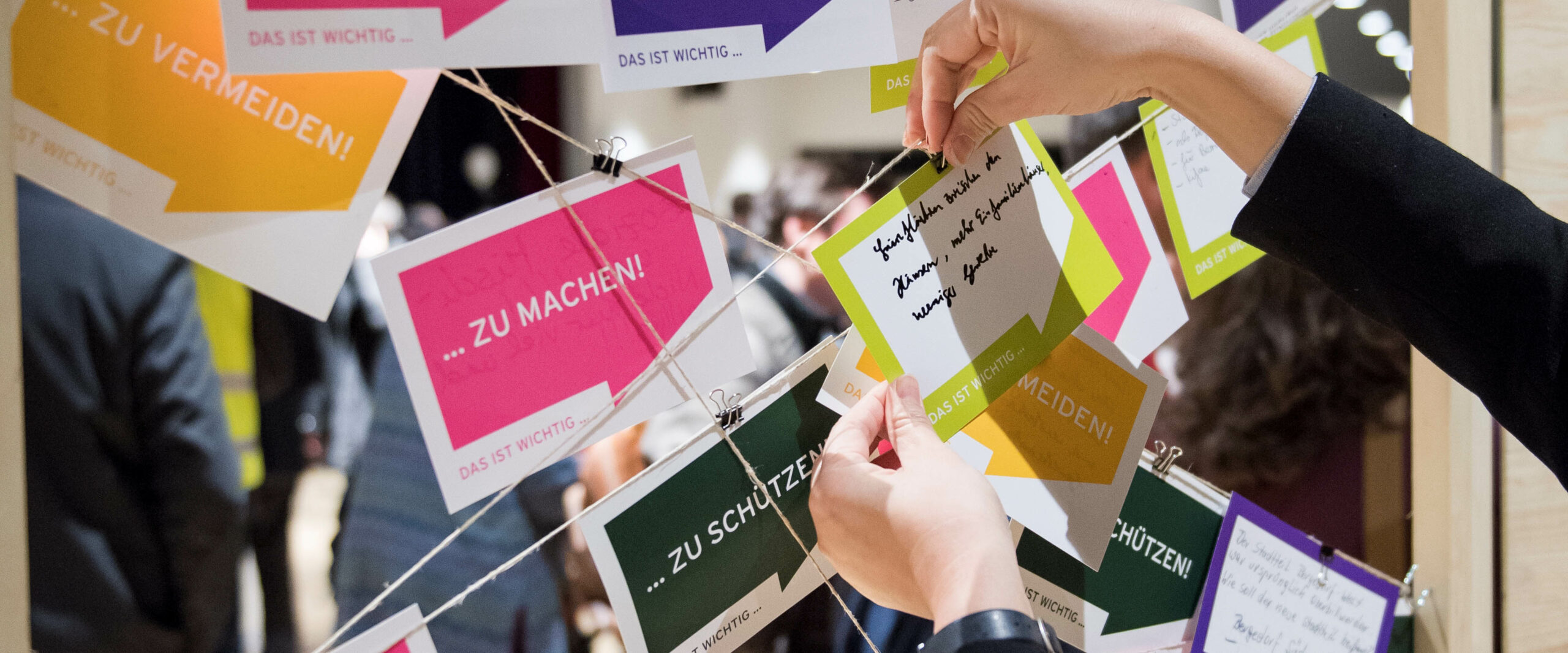 Eine Person hängt eine Notiz an eine Mindmap bestehend aus Schnüren