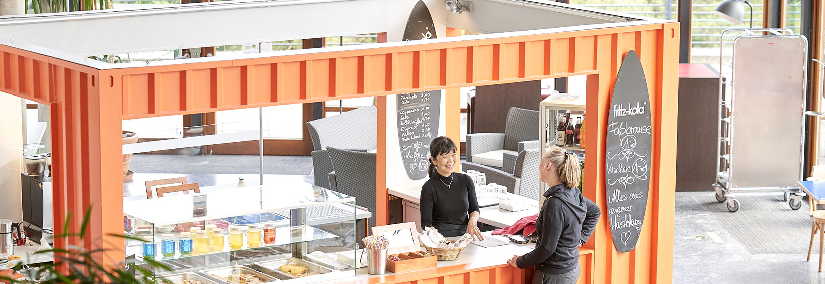 Zwei Personen unterhalten sich an einem Cafétresen
