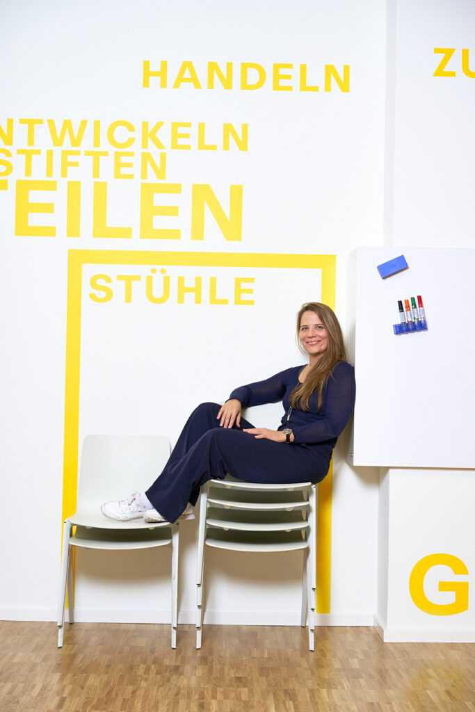 Dorothea Kerrutt sitzt auf einem Stapel Stühle