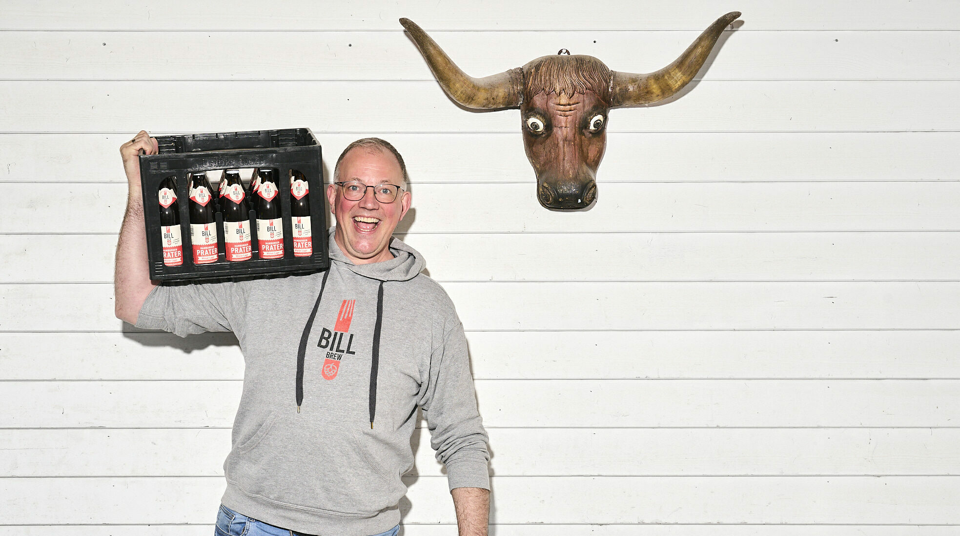 Christian Temme mit einem Bierkasten auf der Schulter, neben ihm hängt ein Stierschädel an der Wand